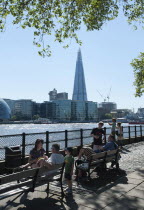 England, London, People relaxing on the North Bank of the river Thames with the Shard visible behind.