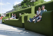 England, London, Tourists relax in giant green astro turf covered sofas on the South Bank of the river Thames.