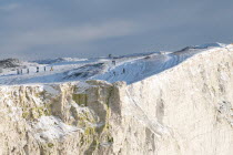 England, East Sussex, Seaford Head, snow on cliffs with people toboganing.