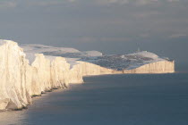England, East Sussex, Seven Sisters, Snow covered coastline from Birling gap showing the coastguard Cottages in the foreground and Belle Tout lighthouse in the distance.