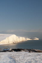 England, East Sussex, Seven Sisters, Snow covered coastline from Birling gap showing the Coastguard cottages in the foreground and Belle Tout lighthouse in the distance.
