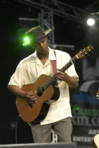 England, Cambridge Folk Festival, Eric Bibb performing on stage with acoustic guitar.