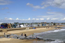 England, Suffolk, Southwold, Beach Huts near the pier with Sea Defences and Holidaymakers.