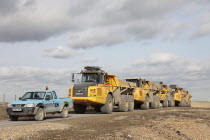 Construction, Machines, Convoy of yellow Volvo Dump Trucks used to redistribute pebbles on shingle beach.