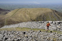 Ireland, County Down, Mourne Mountains, a hiker on Slieve Donard with Slieve Commedagh behind.