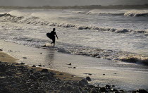 Ireland, County Sligo, Strandhill, silhouette of surfer with surfboard heading into the sea .