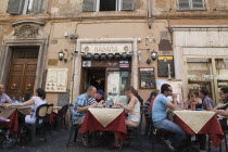 Italy, Lazio, Rome, Diners eating al fresco at a restaurant in a back street.