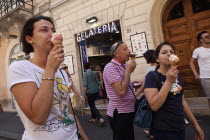 Italy, Lazio, Rome, Eating ice cream outside a Gelateria in a back street.