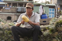 Vietnam, Mekong Delta, Man cutting a pineapple in the floating market at Cai Rang near Can Tho.