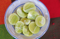 Mexico, Oaxaca, Huatulco, Blue and white bowl with cut halves of limes on red and green woven cloth.
