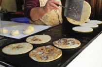 Mexico, Bajio, San Miguel de Allende, Cropped shot of woman making tortillas, turning them as they cook on griddle.