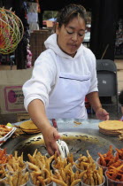 Mexico, Michoacan, Patzcuaro, Young woman frying fish.
