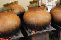 Mexico, Oaxaca, Large, earthenware pots of food cooking over hot coals.