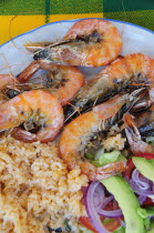 Mexico, Oaxaca, Hualtulco, Gambas or prawns served on blue and white plate with sliced onion, avocado, tomato and couscous salad.