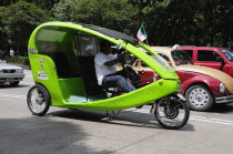 Mexico, Federal District, Mexico City, Pedi taxi and VW taxi waiting on road.