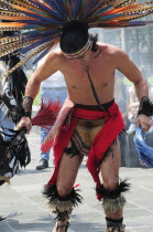 Mexico, Federal District, Mexico City, Michacoa Aztec dancer wearing brightly coloured feather head-dress, performing in the Zocalo.