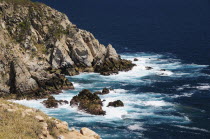 Mexico, Oaxaca, Huatulco, Waves breaking against rocky coastline.