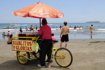 Mexico, Veracruz, Snack seller on Playa Villa del Mar with people on beach and in sea.