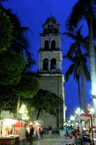 Mexico, Veracruz, Stalls in the Zocalo with the cathedral bell tower behind, at night with illuminated street lights.