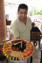 Mexico, Veracruz, Sweet seller in the Zocalo displaying large plate with variety of sweets.