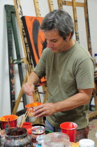 Mexico, Bajio, San Miguel de Allende, Artist Juan Ezcurdia in his studio mixing paint.