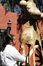 Mexico, Bajio, San Miguel de Allende, Artist Alejandro Lopez with sculpture at his studio.