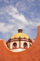 Mexico, Bajio, San Miguel de Allende, Dome of the Parroquia church part framed by orange painted wall.