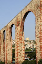Mexico, Bajio, Queretaro, Aquaduct arches framing view towards city buildings on hillside beyond.