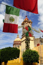 Mexico, Bajio, San Miguel de Allende, Mexican flags and Independence Day decorations hang in foreground of church.