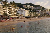 Mexico, Jalisco, Puerto Vallarta, View of Playa Los Muertos beach overlooked by hotels and apartments and lined with bars, cafes and beach shades. People on beach and in the water.