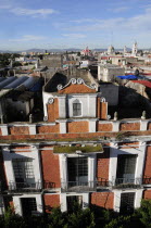 Mexico, Puebla, View across city rooftops with red brick and white facade of building in foreground.