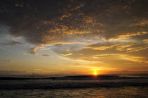 Mexico, Oaxaca, Puerto Escondido, Sunset over Playa Zicatela with waves breaking on shore.