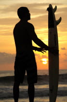 Mexico, Oaxaco, Puerto Escondido, Surfer and board silhouetted at sunset on Playa Zicatela.