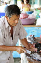 Mexico, Oaxaca, Puerto Escondido, Playa  Principal, Man preparing fresh fish in the market.
