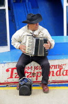 Mexico, Michoacan, Patzcuaro, Lago Patzcuaro, Musician playing the accordion sitting on painted boat.