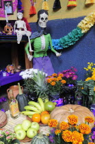 Mexico, Michoacan, Patzcuaro, Dia de los Muertos, Day of the Dead, altar with skeleton figures, food and drink and colourful paper decorations.