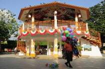 Mexico, Veracruz, Papantla, Balloon seller walking past brightly painted bandstand in the Zocalo.