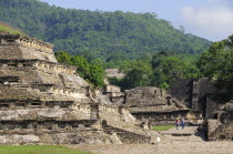 Mexico, Veracruz, Papantla, El Tajin archaeological site, View of Tajin Viejo site with hills behind tourist couple in middle foreground.