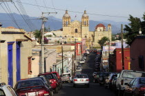 Mexico, Oaxaca, View along street lined by parked vehicles towards church of Santo Domingo.