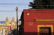 Mexico, Oaxaca, View towards church of Santo Domingo from street corner and red and ochre painted building.