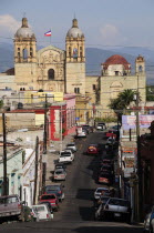 Mexico, Oaxaca, View along street lined with parked vehicles towards church of Santo Domingo.
