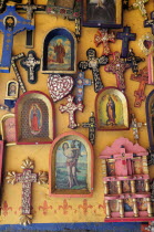 Mexico, Michoacan, Patzcuaro, Religious, kitsch art displayed on yellow painted wall.