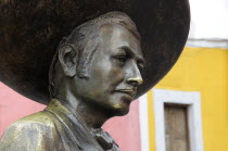 Mexico, Bajio, Guanajuato, Bronze statue of Charro singer Jorge Negrete with pink and yellow painted building facade behind.