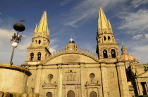 Mexico, Jalisco, Guadalajara, Plaza Guadalajara, Cathedral exterior facade and bell towers with part view of fountain in foreground.