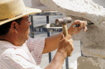 Mexico, Jalisco, Guadalajara, Plaza de la Liberacion, Sculptor working stone with hammer and chisel