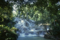 West Indies, Jamaica, Ocho Rios, Dunns River Falls, waterfall tumbling over rocks surrounded by trees and vegetation.