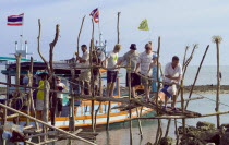 Thailand, Koh Samui, Thong Krutt fishing village, tourists disembarking from a wooden boat after a fishing day trip.