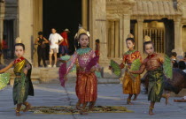 Cambodia, Siem Reap, Angkor, Angkor Wat, child dancers in traditional dress with tourists framed by temple entrance behind.