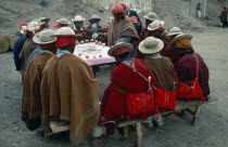 Bolivia, La Paz, Amarete, Fiesta de San Felipe held on May 1st, group of men sat around table being served hot drink.