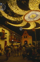 Colombia, Antioquia, Medellin, Christmas lights at Cerro Nutibara, crowds in small cobbled square under illuminated lights at night.